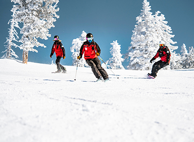 three female patrollers ski down the slope at diamond peak ski resort 